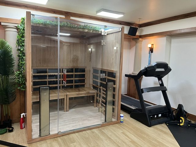 Infrared sauna in cedar and glass set beside the treadmill