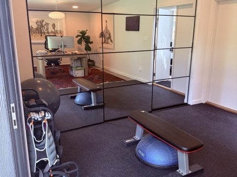 Mirrored training nook with a bench and upright bike behind a glass partition