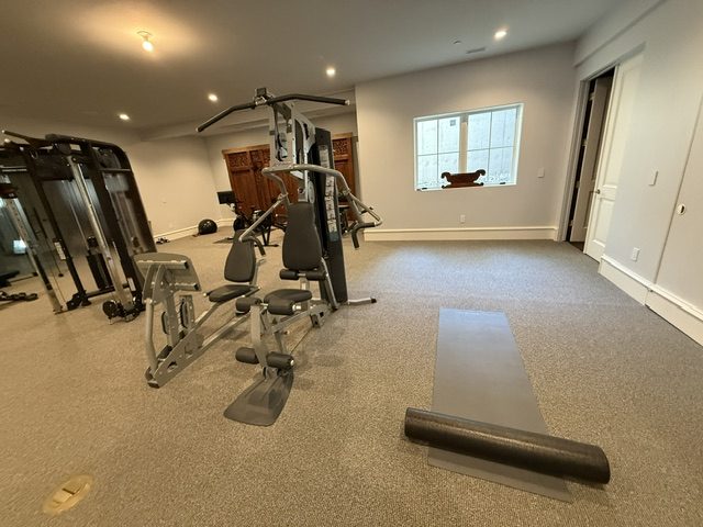 Dedicated home gym with a multi-station strength machine and open floor for mat work