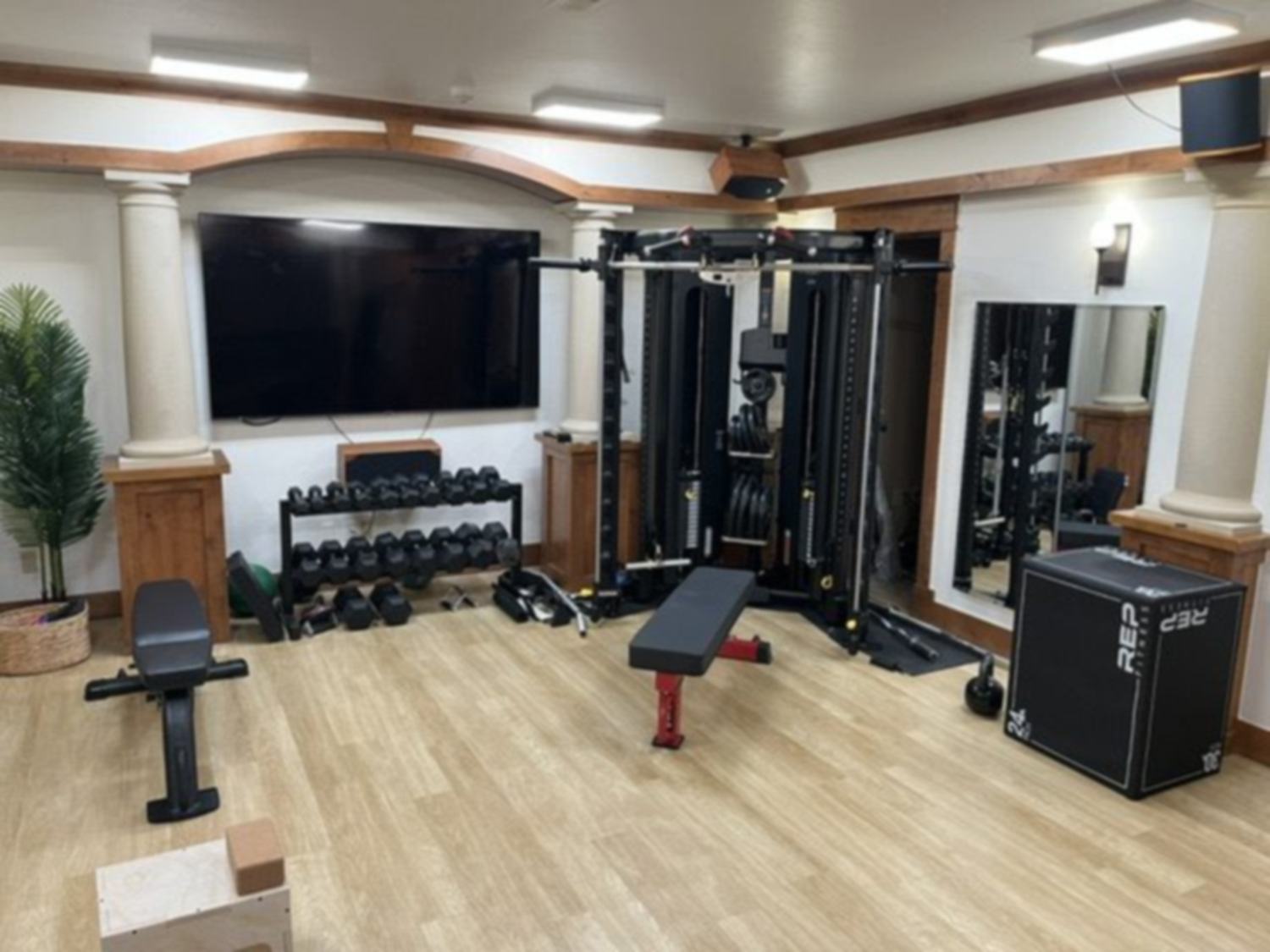 A completed luxury home gym with functional trainer and free weights