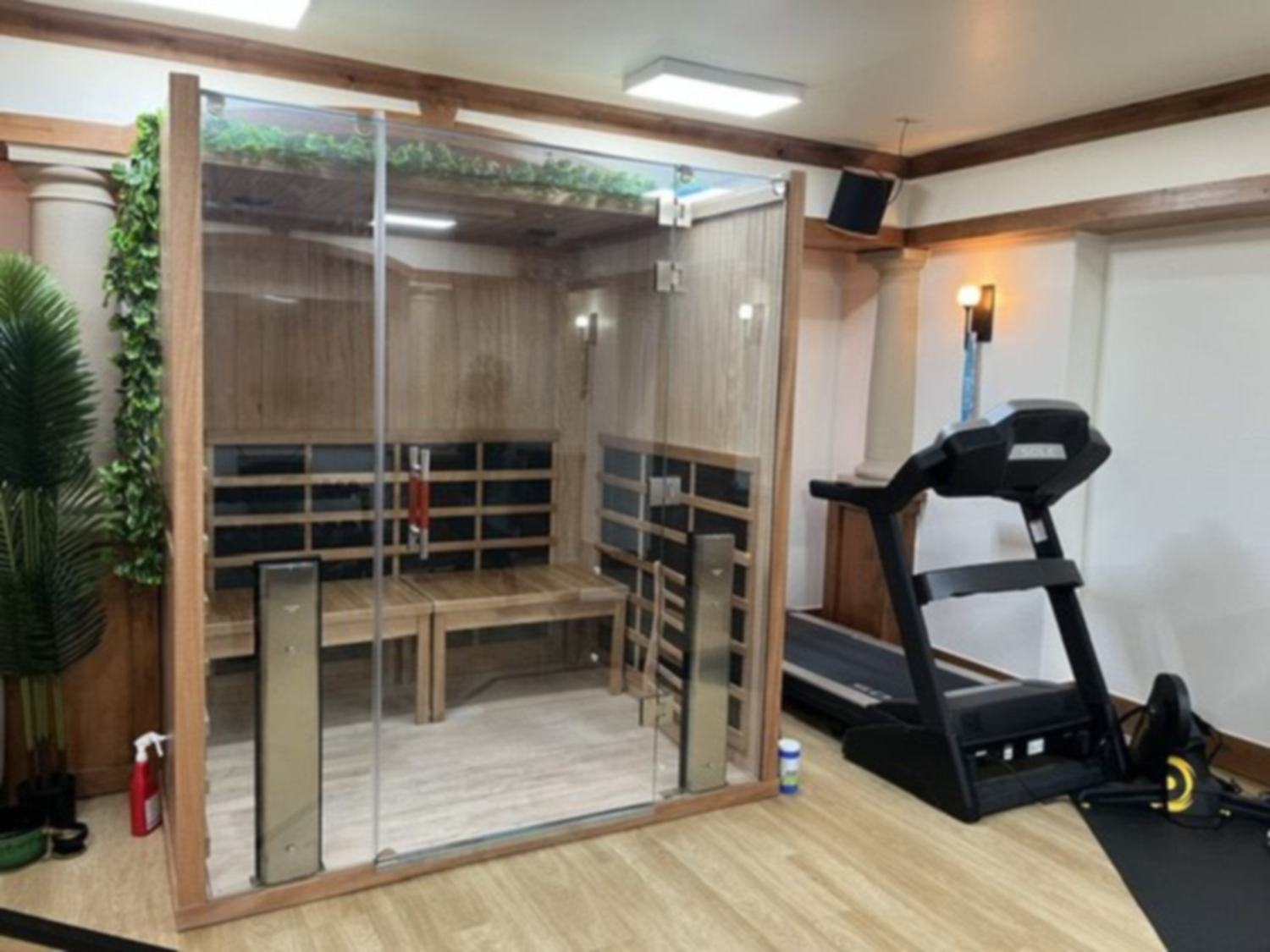 An infrared sauna set beside the treadmill in a home gym